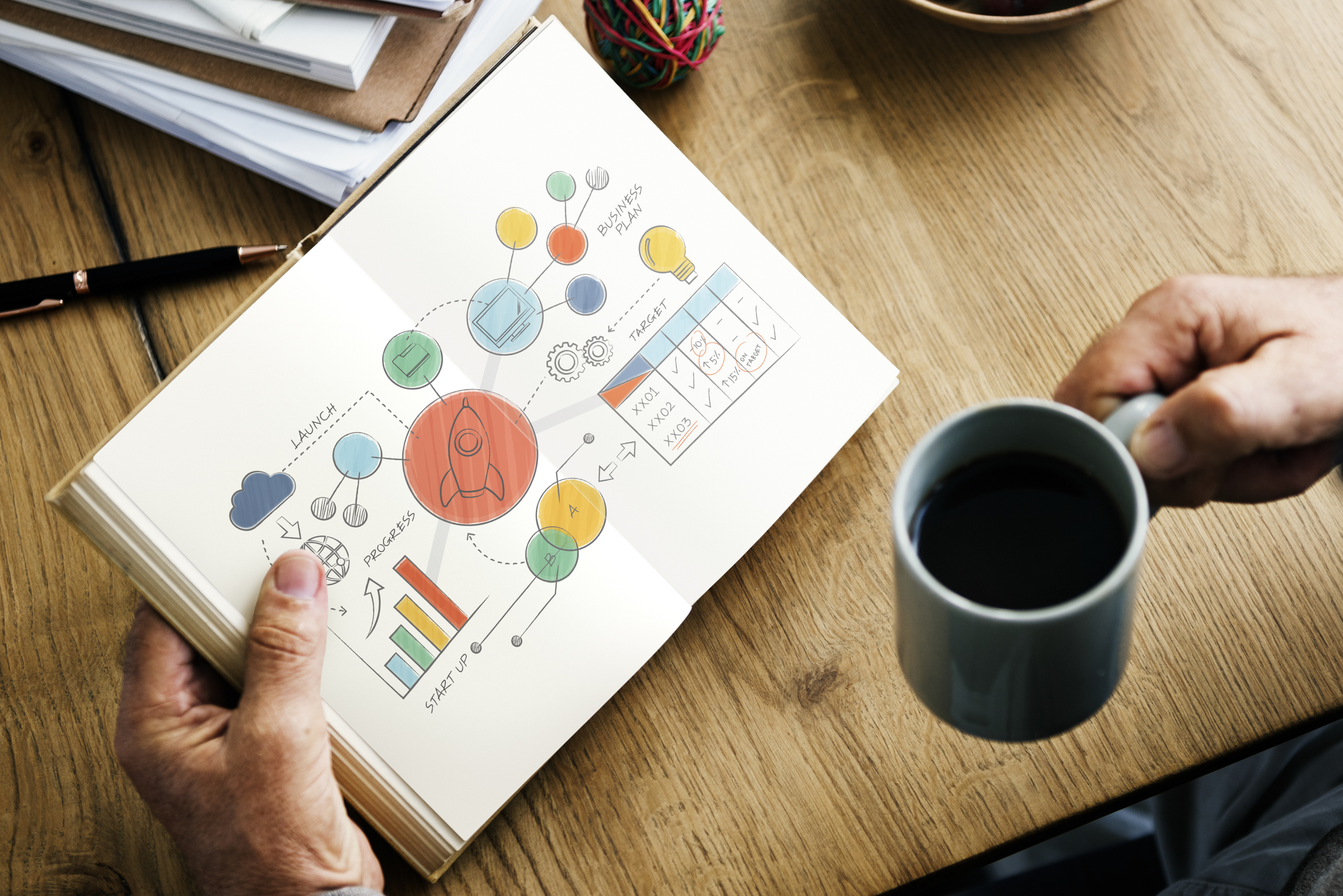 Closeup of hands holding open novel and coffee cup
